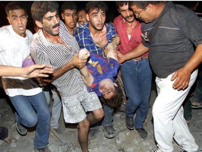 Palestinians carrying a badly injured  child as a result of an Israeli bombing of flats in Gaza