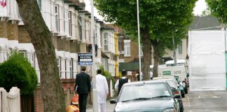 Police escort resident to his door in Lansdown Road, Forest Gate, yesterday midday, with number 46 hidden by plastic sheeting