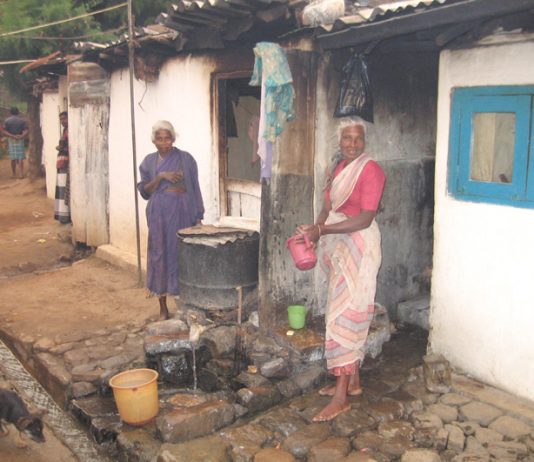 Sewage waste runs in the open drain – only feet away from where these Tamil plantation workers cook their food