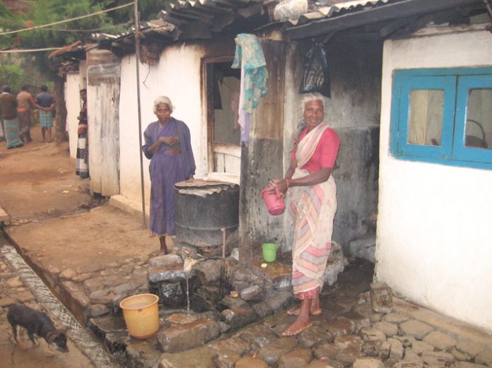 Sewage waste runs in the open drain – only feet away from where these Tamil plantation workers cook their food