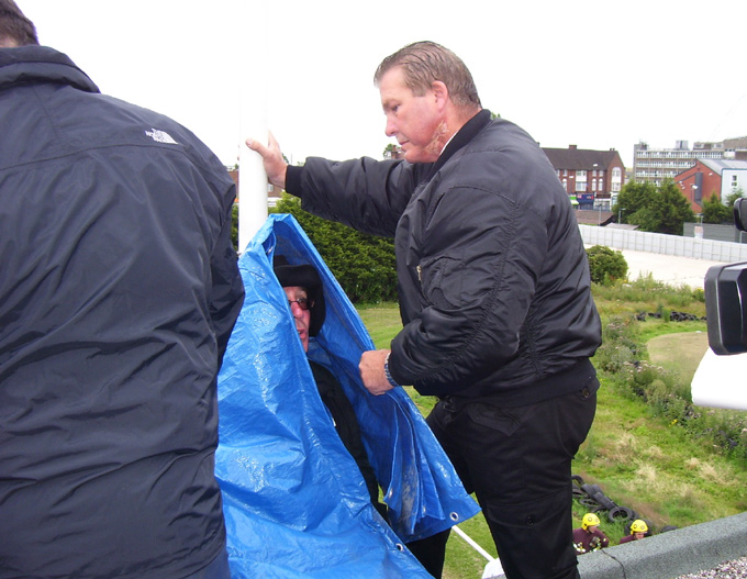 Council bailiffs wrap anti-academy protester HANK ROBERTS (who had D-locked himself on the roof) in a cover before using an angle grinder to release and evict him last Friday morning