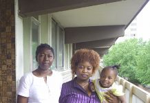 EVELYN, holding her daughter, with neighbour FELICIA on the Heygate estate