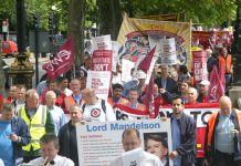Postal workers marching along the embankment carrying a giant postcard to Business Secretary Mandelson demanding he stop destroying a great public service