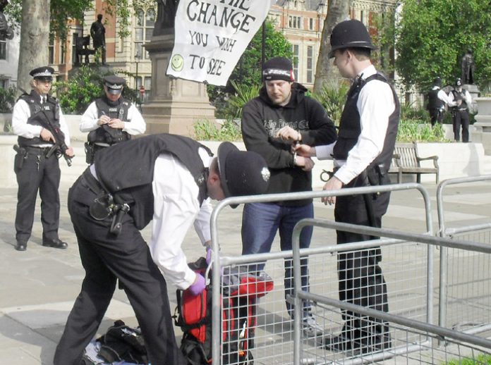 Armed police arrest and handcuff one of the peace protesters as they search his bag in Parliament Square yesterday morning