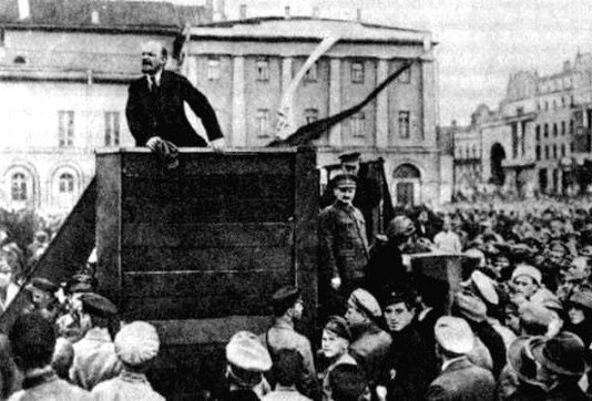 TROTSKY stands by as LENIN addresses a mass meeting in Petrograd