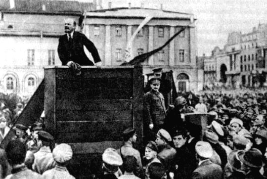 TROTSKY stands by as LENIN addresses a mass meeting in Petrograd