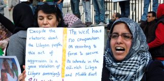 Woman holds her own detailed placard on a protest over the war on Libya earlier this year