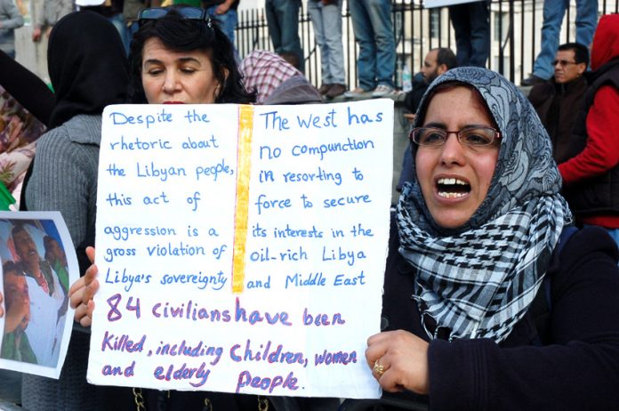 Woman holds her own detailed placard on a protest over the war on Libya earlier this year