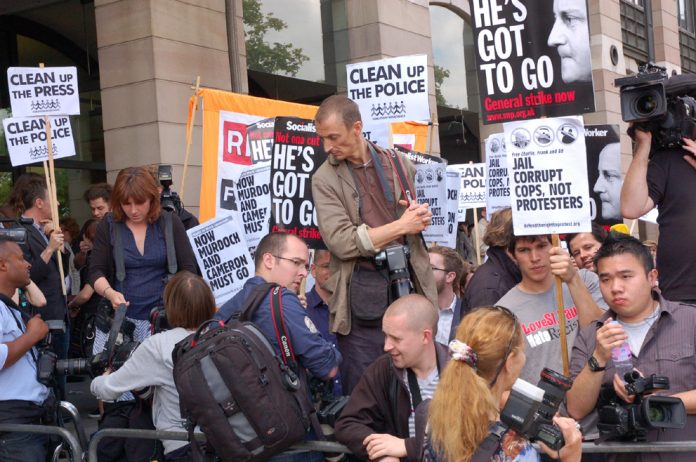 Demonstrators outside yesterday’s hearings where MPs questioned the Murdochs and sacked police chiefs, demanding that Cameron and Murdoch go