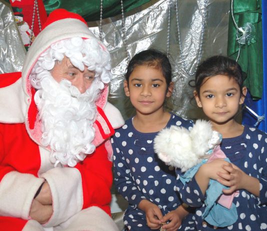 Father Chrismas with two young children at the Young Socialists Xmas Bazaar – many children will be going without this Christmas