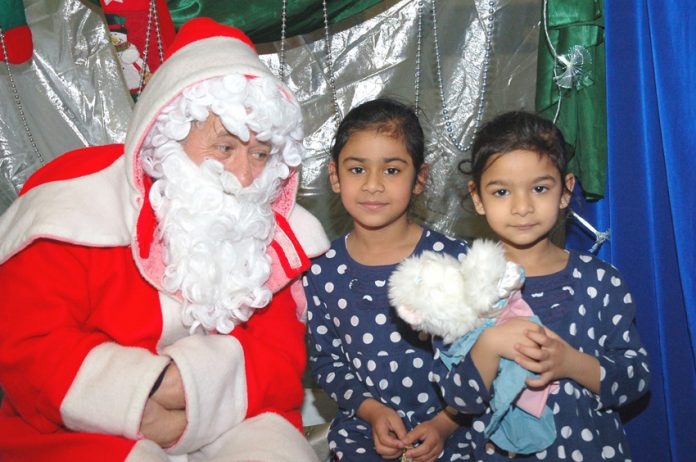 Father Chrismas with two young children at the Young Socialists Xmas Bazaar – many children will be going without this Christmas