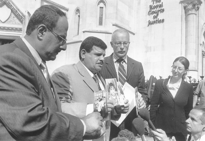 The father of Baha Mousa, the Iraqi hotel worker beaten to death by British troops holds photos of his son’s family outside the High Court in London in July, 2004