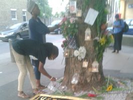 The banner of the Sean Rigg Justice and Change Campaign under a memorial to him outside Brixton Police station