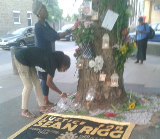 The banner of the Sean Rigg Justice and Change Campaign under a memorial to him outside Brixton Police station