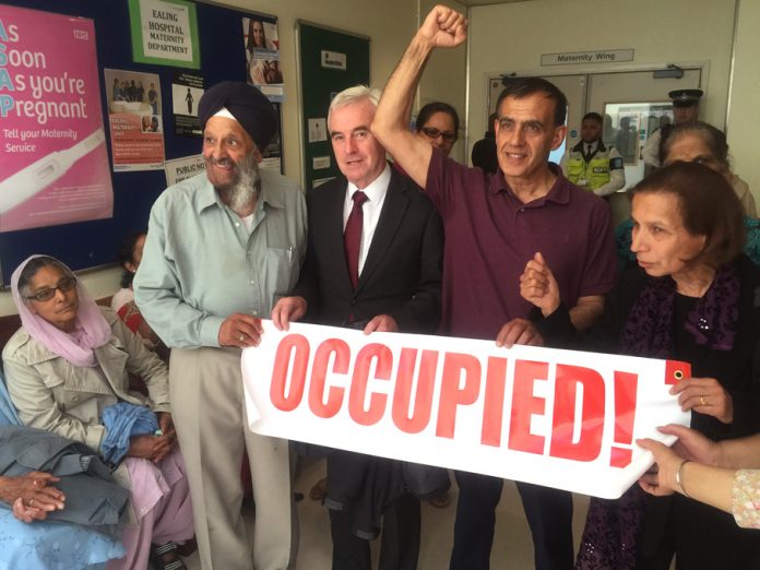 Labour MP for Hayes and Harlington John McDonnell holding the occupied banner with workers from Southall inside the maternity department