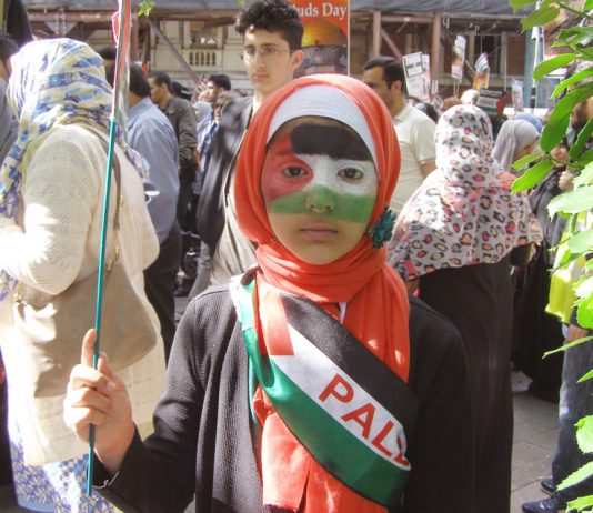 A young girl on the march proud to display the colours of the Palestinian flag