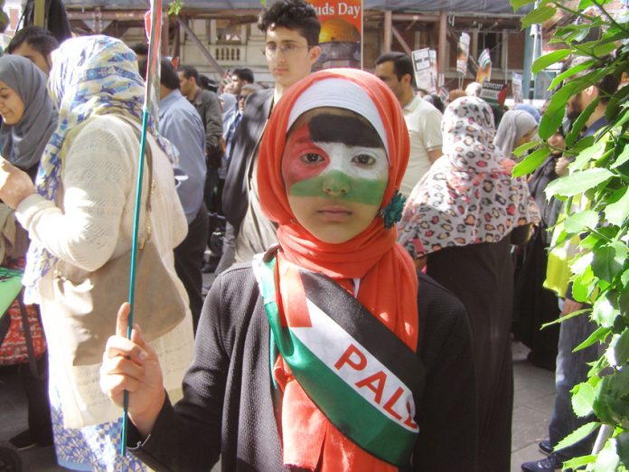 A young girl on the march proud to display the colours of the Palestinian flag