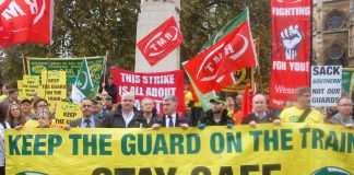 RMT president SEAN HOYLE, assistant general secretary STEVE HEDLEY and general secretary MICK CASH (all behind the banner from the front, left) on the union’s 300-strong protest opposite parliament against driver-only trains