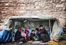 Refugee family – trying to keep alive from cold in a flimsy shelter. Photo credit: Panos Papanikolaou