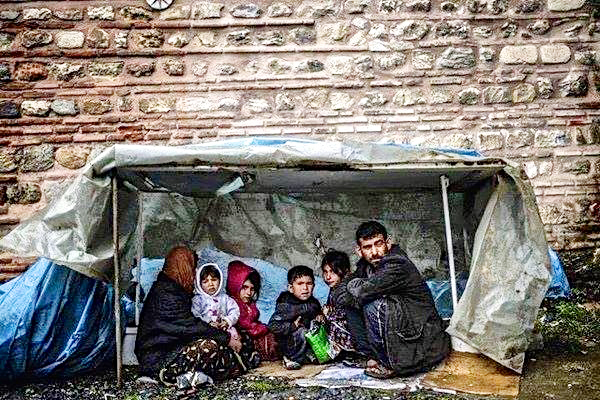 Refugee family – trying to keep alive from cold in a flimsy shelter. Photo credit: Panos Papanikolaou