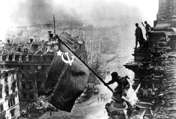 A Red Army soldier raises the Hammer and Sickle above the Reichstag, completing its liberation of Eastern Europe