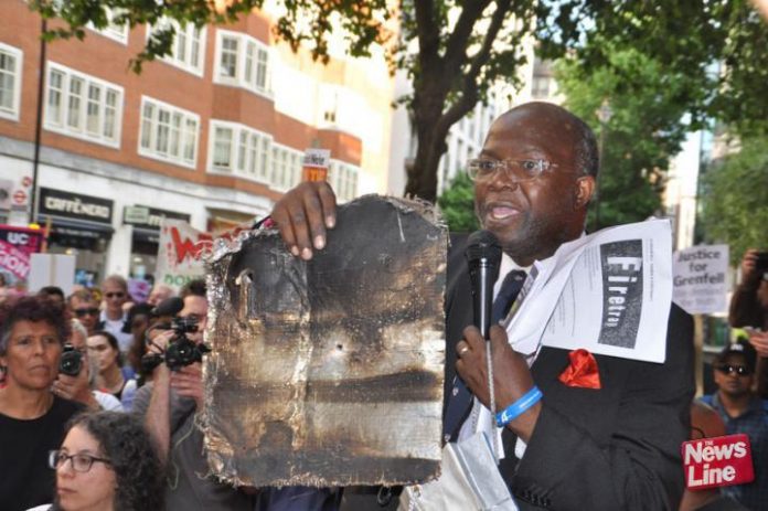 Grenfell resident holds up a piece of charred cladding which had fallen during the Grenfell Tower inferno