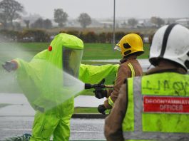 Firefighter in decontamination suit being hosed down