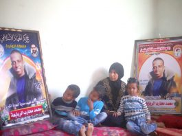 Muhammad al-Rabaia’s mother and three sons sit beside posters honoring their slain father and son. Photo credit: Abed Zagout