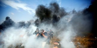 Palestinians emerge through clouds of teargas fired by Israeli troops at the Gaza border on the 6th Friday demonstration yesterday