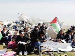 Palestinian children struggle to study in the open air after their school was bombed by Israeli forces