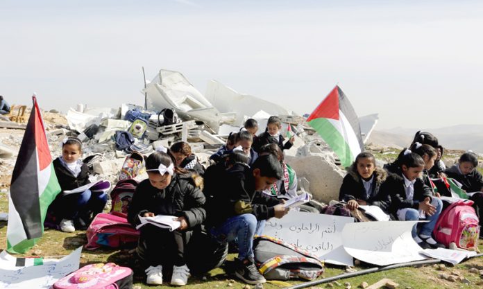 Palestinian children struggle to study in the open air after their school was bombed by Israeli forces