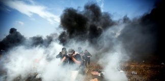 Young Palestinian demonstrators escaping the bombardment of tear gas and bullets from Israeli Defence Forces at the Gaza-Israel border fence