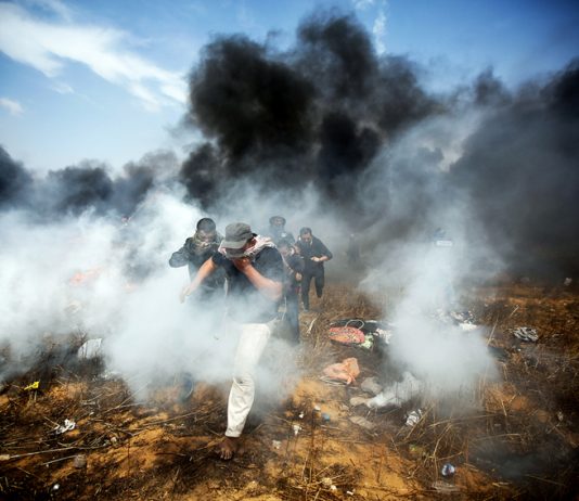 Young Palestinian demonstrators escaping the bombardment of tear gas and bullets from Israeli Defence Forces at the Gaza-Israel border fence