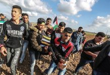 Palestinian youth carry a man injured after being shot by Israeli forces on the Gaza border