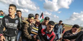 Palestinian youth carry a man injured after being shot by Israeli forces on the Gaza border