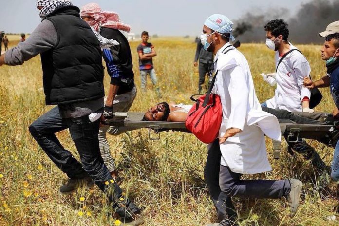 Palestinian wounded by Israeli sniper fire on the Gaza border is carried to safety