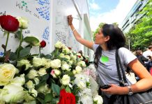Writing tributes on the memorial at the base of Grenfell Tower yesterday