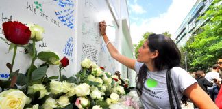 Writing tributes on the memorial at the base of Grenfell Tower yesterday