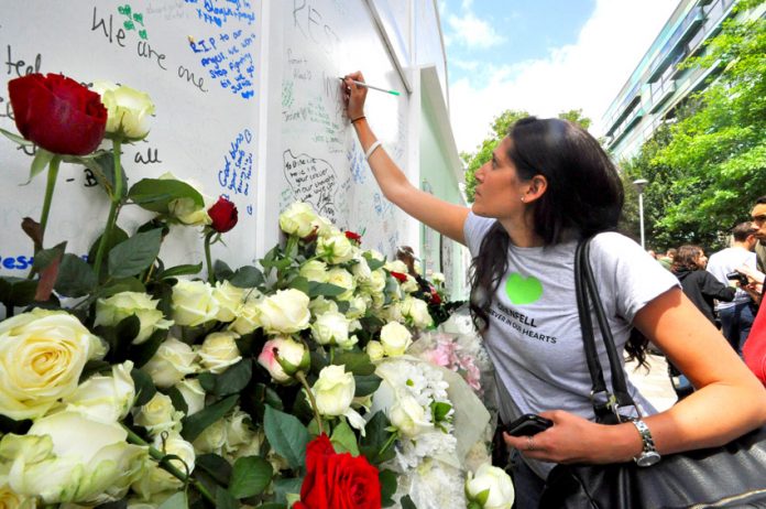 Writing tributes on the memorial at the base of Grenfell Tower yesterday