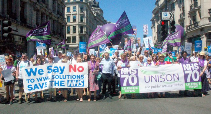 Unison members on the NHS 70th anniversary demonstration in London with (left) strikers from the Wrightington, Wigan & Leigh hospital over plans to transfer their jobs to a private company