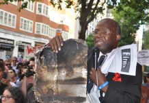 A local resident holds up the charred remains of Grenfell Tower cladding – 468 buildings across the UK are clad in the same flammable aluminium composite – the Tories refuse to ban it