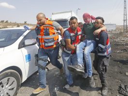 Medics help a Palestinian student on a protest against Israel’s racist Nation State law after he was shot by Israeli troops