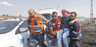 Medics help a Palestinian student on a protest against Israel’s racist Nation State law after he was shot by Israeli troops