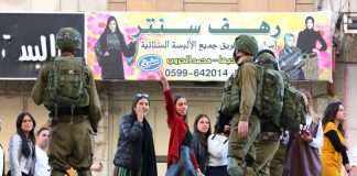 Palestinian girls in Hebron defy the occupying Israeli troops (above) after they had blocked off a road in the city on Friday (below) to allow access to Israeli settlers
