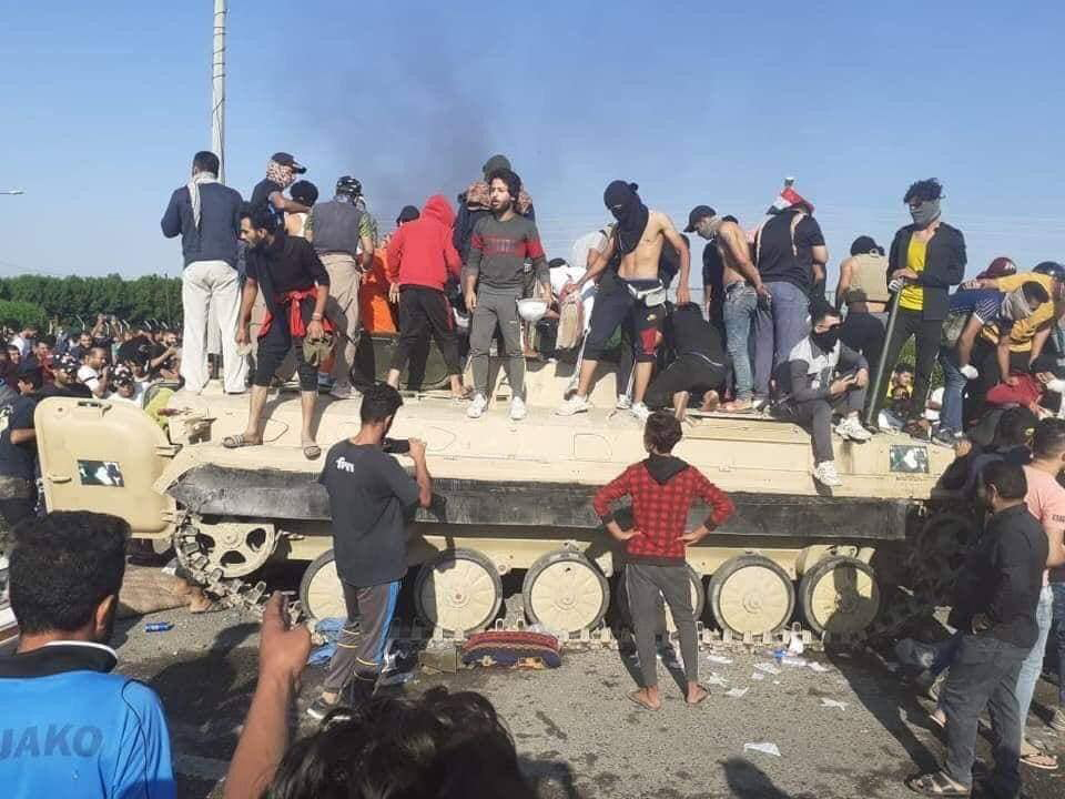 Iraqi young people aboard a captured military vehicle in Baghdad